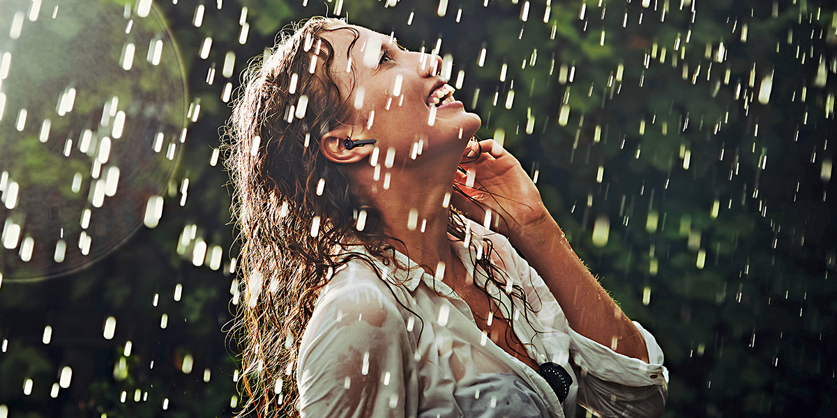 一位女士在雨中沒有撐傘，通過采用GORE?聲學透氣產品的耳機接聽電話。